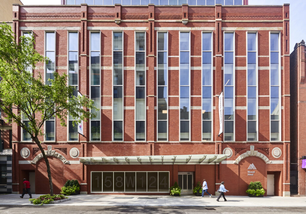 An exterior image of vertical glass windows and a brick facade
