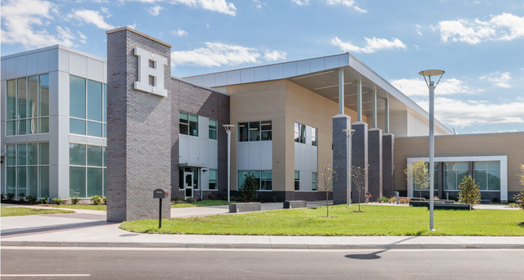 high school exterior|high school building exterior|high school students socializing in hallway|high school students learning science|high school students learning healthcare|high school building exterior|high school building exterior|social staircase in cafeteria|students socializing in cafeteria|students socializing outside|high school auditorium for performances|students reading in library|high school gymnasium|high school outdoor courtyard with ping pong tables and students||||||||||||||||||||||||||