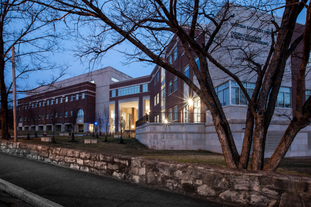 A brick building is lit up at dusk.|higher education exterior building|higher education building exterior nighttime|higher education students learning science lab|higher education students learning science lab|higher education hallway student collaboration|higher education building lecture auditorium classroom|higher education building interior design hallway|higher education outdoor building exterior||||||||||||||||