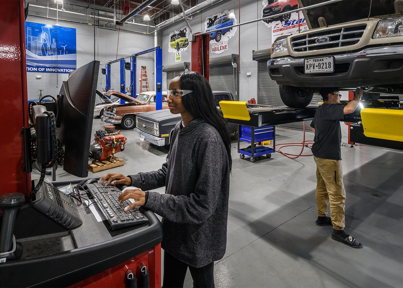 Female Student learning in an automotive mechanic space designed by Huckabee Architects